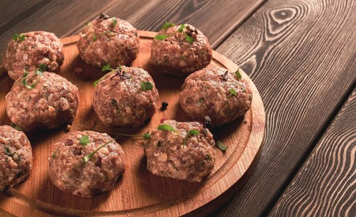 Raw meatballs, with micro greenery, on a cutting board, homemade, rustic, no people
