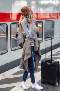 Young woman standing on the railway track in front of a train