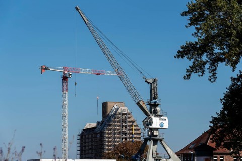 Old silo building, warehouse, in front of it construction crane and harbour crane, Magdeburg Port