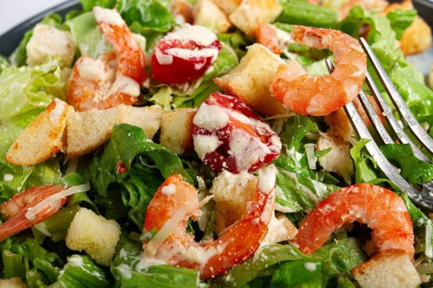 Caesar salad, with shrimp, on a marble background, top view, no people