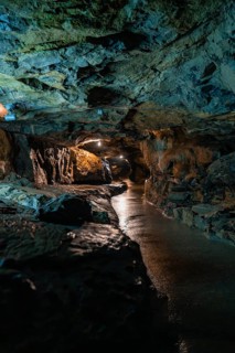 Dark cave made of rocks with water and artificial lighting, mysterious atmosphere, Beatus Caves,