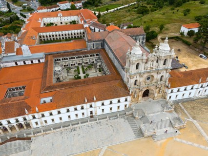 Historic monastery with red roof and courtyard, surrounded by landscape, aerial view, Mosteiro de