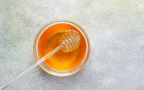 Spoon with honey, on the table, spindle for honey, close-up, rustic view