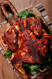 Whole fried chicken, with spices, grilled chicken, on a chopping board, top view, homemade, no