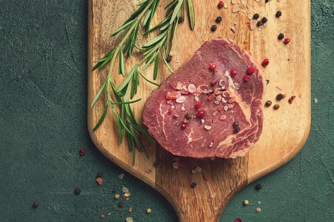 Fresh, raw rib eye steak, on a chopping board, top view, no people