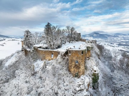 Aerial view of the snow-covered Hegau volcano Mägdeberg with remains of a castle wall on a cold