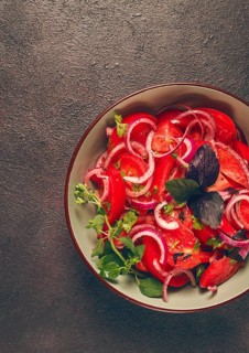 Fresh tomato salad, with red onion, spices and herbs, top view, close-up, homemade
