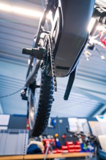 View of a bicycle chain and a wheel from below in a workshop, Waldbike Manufaktur, bicycle