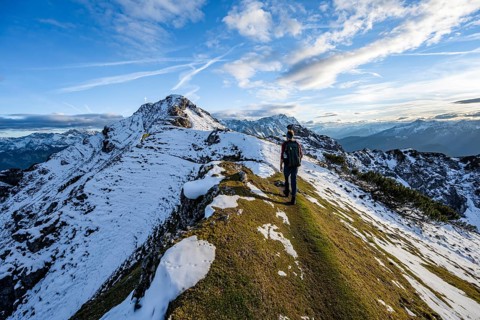 Mountaineer on hiking trail, mountain landscape with snow in autumn, summit and ridge of the
