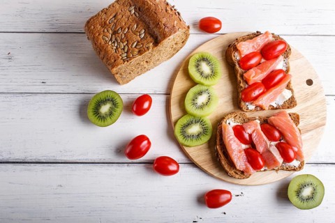 Smoked salmon sandwiches with butter and cherry tomatoes on white wooden background. top view, copy