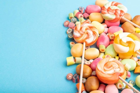 Various caramel candies on blue pastel background. copy space, side view
