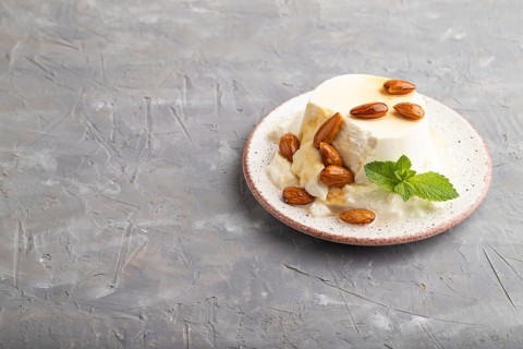 Ricotta cheese with honey and almonds on gray concrete background. side view, copy space