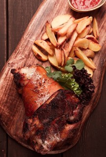 Pork knuckle, in soy-honey sauce, with fried potatoes, on a wooden chopping board, homemade, no