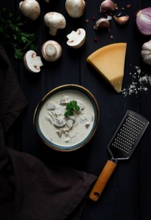 Cream sauce with mushrooms, top view, on a dark gray wooden table, horizontal, no people