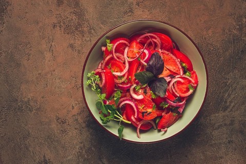 Fresh tomato salad, with red onion, spices and herbs, top view, close-up, homemade