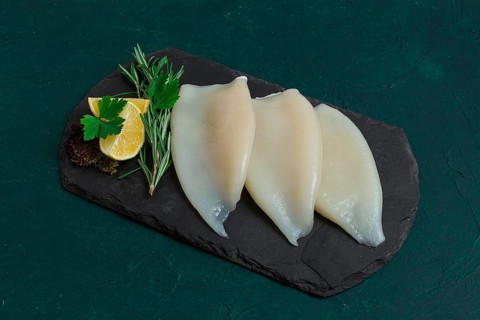 Fresh squid body, raw, three carcasses, top view, on black slate, no people