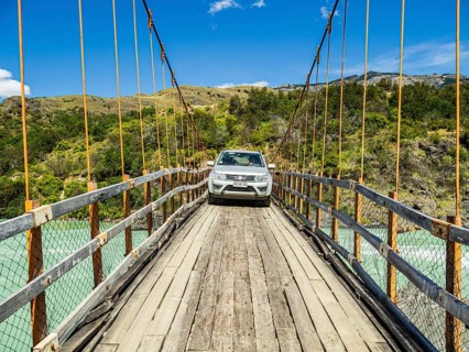Small car (suv) crossing the river Rio Baker on an old suspension brige, bridge suitable for cars