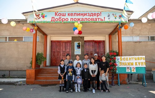 Family and school children, group posing in front of the school on the first day of school,
