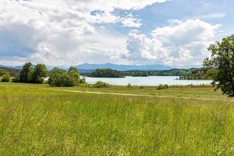 Extensive meadow landscape with a lake and mountains on the horizon under a cloudy sky, Easter