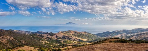 Panoramic view of hilly landscape by the sea under a blue sky, near Tarifa, view to Morocco