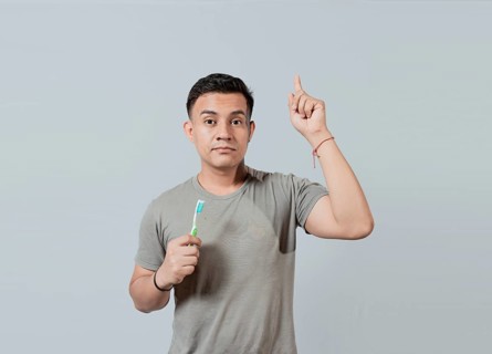 Handsome guy holding toothbrush pointing an advertisement up. Caucasian handsome man holding