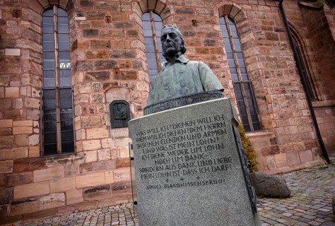 Wilhelm Löhe monument, bronze bust on a high granite stone plinth with three bronze reliefs, by