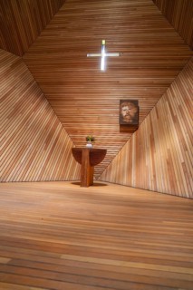 Modern interior of a wooden church with an altar table, flowers and a cross, minimalist design,