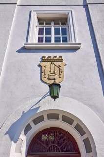 Facade of a whitewashed house in the classicist style with the coat of arms of the salt boiling