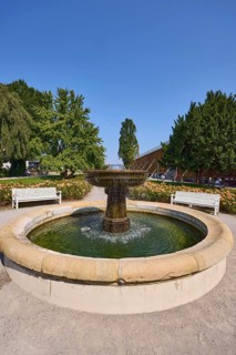 Fountain with benches, graduation tower and trees in the rose garden park in Bad Salzuflen, Lippe