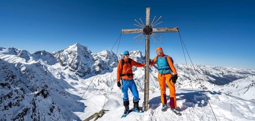 Two ski tourers at the summit cross on the summit of the Madritschspitze, mountain panorama with