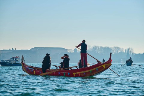 Wild carnival hustle and bustle on the 'Canal Grande' with decorated boats and masked people in