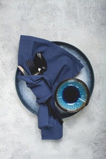 Food background, with an empty blue plate, a bowl, black cutlery, with a napkin, on a gray