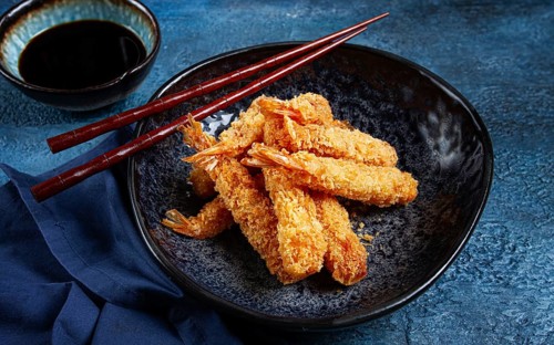 Shrimp in tempura, deep fried, on a black plate, with soy sauce, close-up, top view, no people