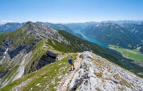 Mountaineer on the hiking trail on the summit ridge of the Unnütz, behind Achensee and summit of