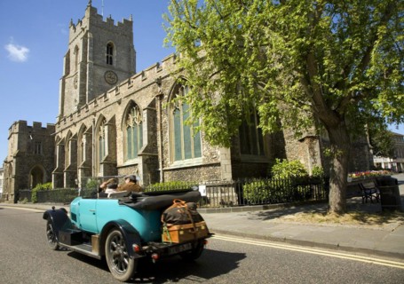 Classic veteran car passing Church of Saint Peter, Sudbury, Suffolk, England, United Kingdom,