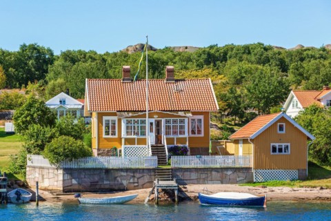 Idyllic summer cottage by a sea beach with a jetty and boats in the Swedish archipelago in the
