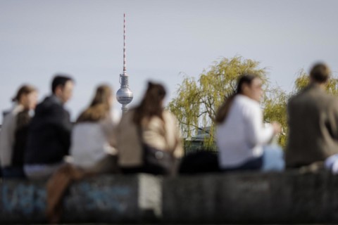 People sitting in the sun on the banks of the Spree in Berlin, 27 March 2024, with the Berlin