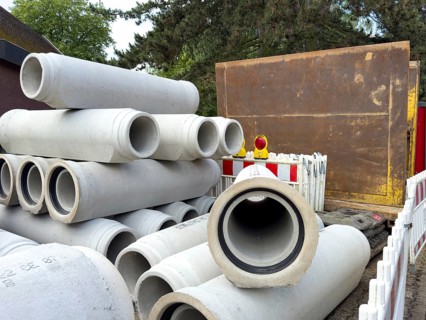 Several concrete pipes stored at the roadside Concrete pipes for sewer construction Laying of sewer