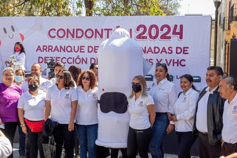 Oaxaca, Mexico, Health workers pose for photos with a person wearing a condom costume as part of