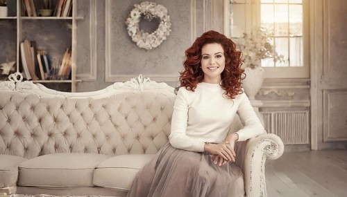 Woman sitting on a stylish sofa in a room with bookshelves and a wreath on the wall, AI generated,
