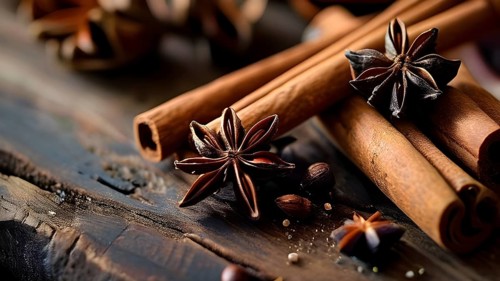 Christmas spices like cinnamon sticks, star anise, and cloves arranged on a wooden table, with soft