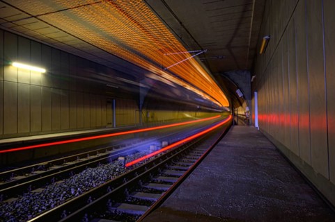 A train races through a tunnel, creating bright streaks of light and conveying a sense of speed,