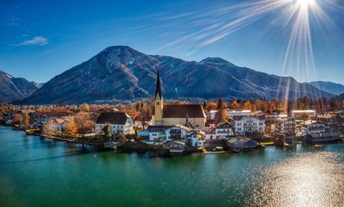 A picturesque lakeside village in an autumn landscape, surrounded by mountains and under a bright