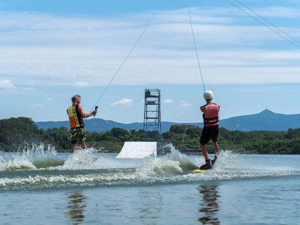 Water sports with wakeboard, two men riding side by side in the lake, camera in hand, water skiing