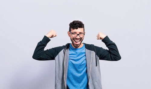 Young man with happy face raising arms in victory gesture isolated. Winner person celebrating