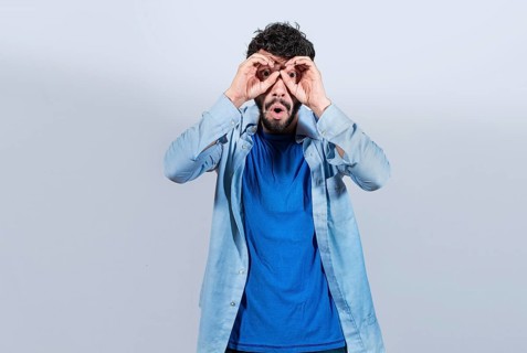 Curious man making binoculars gesture isolated. Guy making binoculars gesture isolated. Man making
