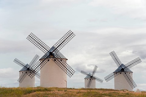 Historic windmills with a cloudy atmosphere. The white colour of the mills contrasts with the grey