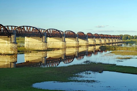 Long, arched stone bridge reflected in the calm river water under a clear sky, autumn, Elbe,