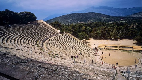 People explore the extensive ruins of an ancient amphitheatre with mountain views, Ancient