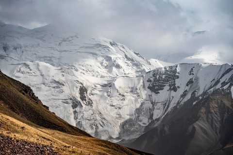 Dramatic mountain landscape, mountain valley, behind glaciated and snow-covered mountain peak Pik